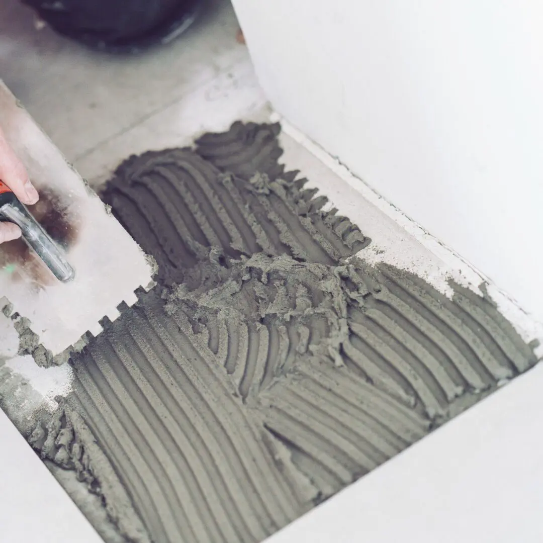 Trowel spreading adhesive on floor